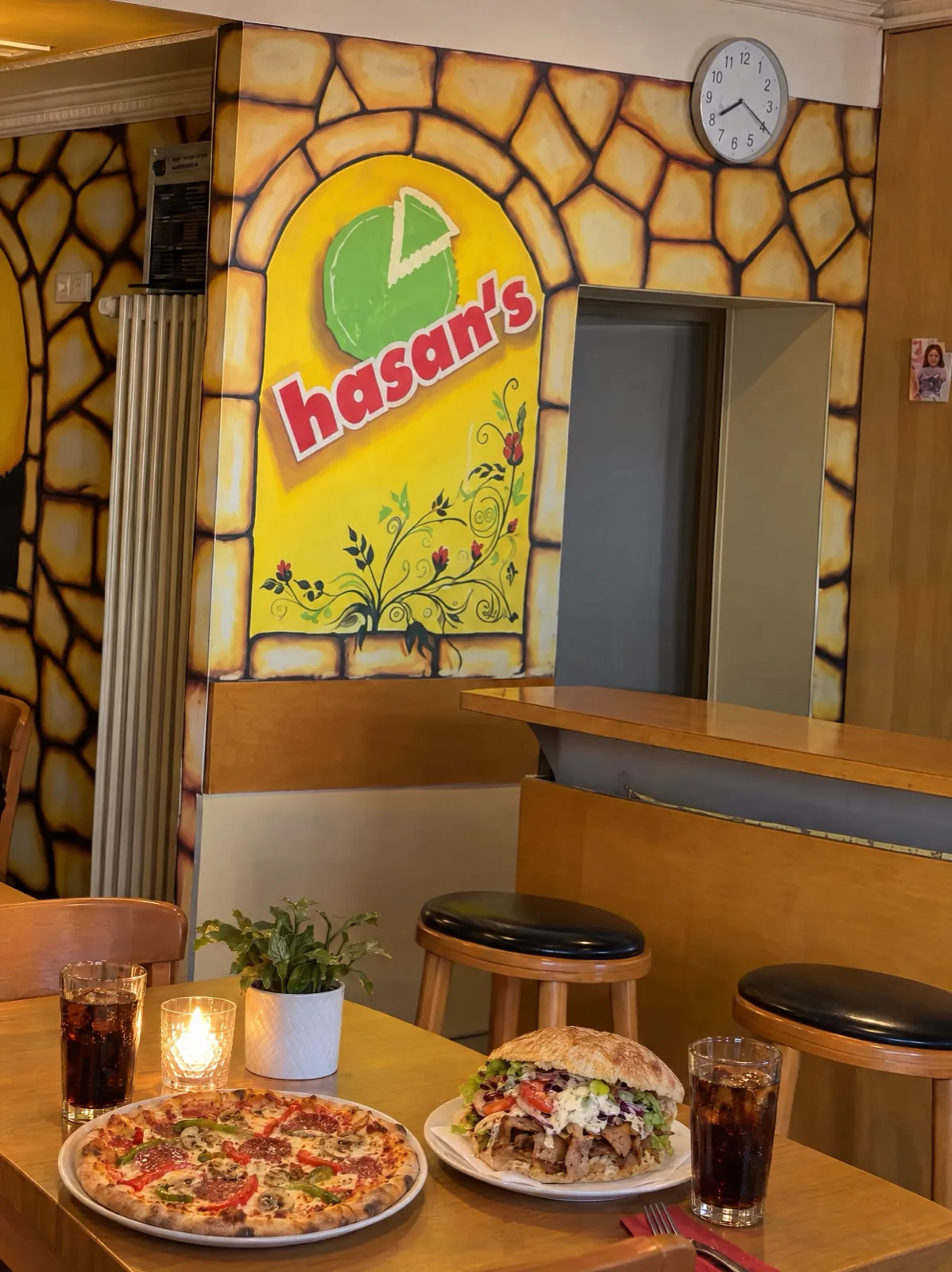 Gedeckter Tisch vor der Logo-Wand mit Pizza und Kebap
